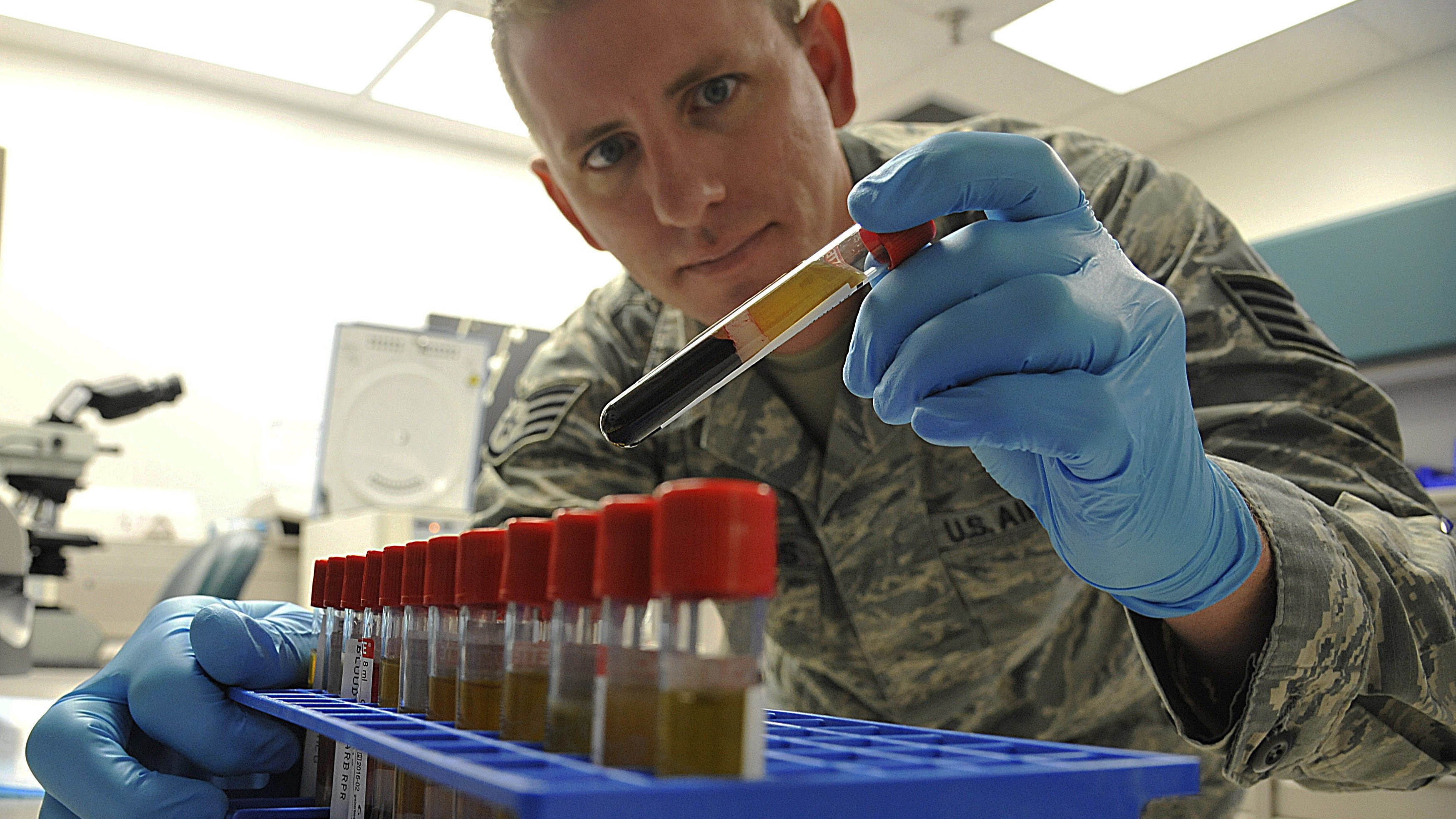 Service member looking at vials of blood