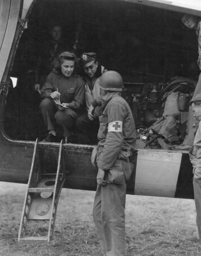 Man and woman in helicopter talking to a medical soldier on the ground