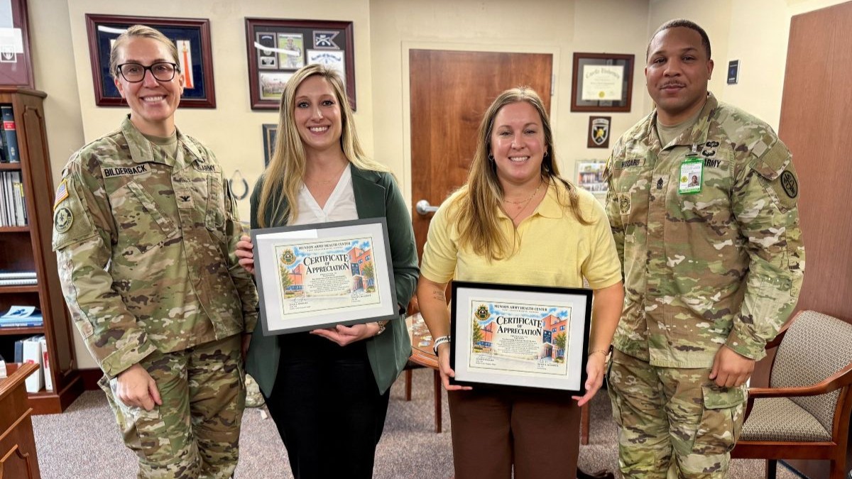 Photo By Maria Christina Yager | Munson Army Health Center Command Team, Col. Tiffany Bilderback and Sgt. Maj. Devon Woodard present certificates of appreciation to The University of Kansas Health System employees from left, Courney Iske and Angie Bobst, during a visit to Munson, Oct. 27. Iske and Bobst run the health systems military training program which provides free trauma education and certifications, clinical immersion, and procedural simulation training for Munson combat medic specialists, physicians, physician assistants, and nurses at its nearby Kansas City, Kansas campus.