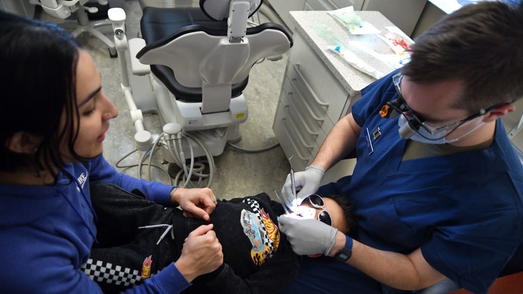 Capt. Jonathan Martino, 55th DS dental resident, right, gives Cameron Fields a military member's child, a knee-to-knee examination at the 55th Dental Squadron’s annual Dental Day in Bellevue, Nebraska, Feb. 7, 2025. The examination is a way for dentists to get an early look at how children’s teeth are developing, detect cavities and screen for illness. (U.S. Air Force photo by D.P. Heard)