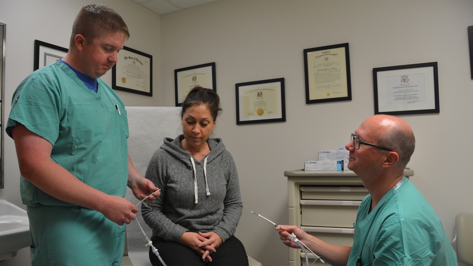 Army Lt. Col. (Dr.) Shane McEntire, a vascular surgeon at Brooke Army Medical Center, shows the device used to perform the TransCarotid Artery Revascularization procedure to Air Force Maj. (Dr.) William Harris, vascular surgeon, and DeAnn Yanez, a nurse in the vascular surgery clinic, Dec. 12, 2017. Surgeons must be specially trained or assisted by someone who has been trained on the device used during the TCAR procedure before they can do this surgery. (U.S. Army photo by Robert T. Shields)