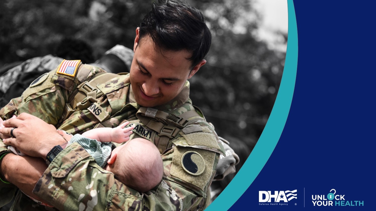 Uniformed soldier holding his baby and smiling