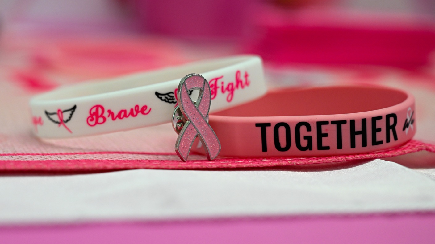 Pink breast cancer awareness bracelets and a ribbon pin are displayed at Wilford Hall's Mammography Clinic, JBSA-Lackland, Texas, on Oct. 3, 2024, as part of National Breast Cancer Awareness Month. Early detection can save lives. (U.S. Air Force photo by Senior Airman Matthew-John Braman)