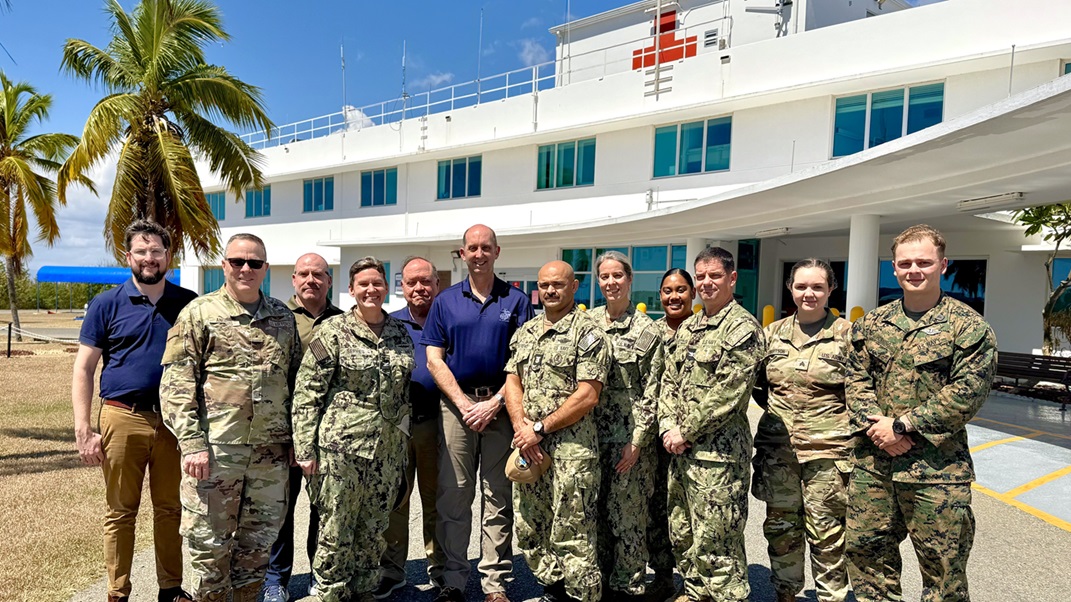 GUANTANAMO BAY, Cuba (Feb. 27, 2025) – Front row, from left, Brig. Gen. John Andrus, Joint Staff Surgeon; U.S. Navy Capt. Tammy Servies, director of U.S. Naval Hospital Guantanamo Bay, commanding officer of U.S. Navy Medicine Readiness and Training Command Guantanamo Bay, commander of Joint Medical Group, Joint Task Force Guantanamo Bay; and Dr. Steven Ferrara, Acting Assistant Secretary of Defense for Health Affairs, pose for a photo with members of his delegation and personnel from U.S. Naval Hospital Guantanamo Bay outside the hospital. The visit provided an opportunity to discuss medical readiness and health care initiatives at the installation. (U.S. Navy photo by Emily McCamy)