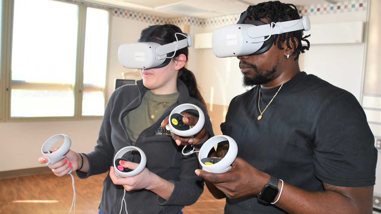 Womack Medical Simulator Operations Specialist, Don-Emeil Watson (R) guides Womack Nurse Lt. Gabrielle Meyo through a VR scenario on March 26, 2025.