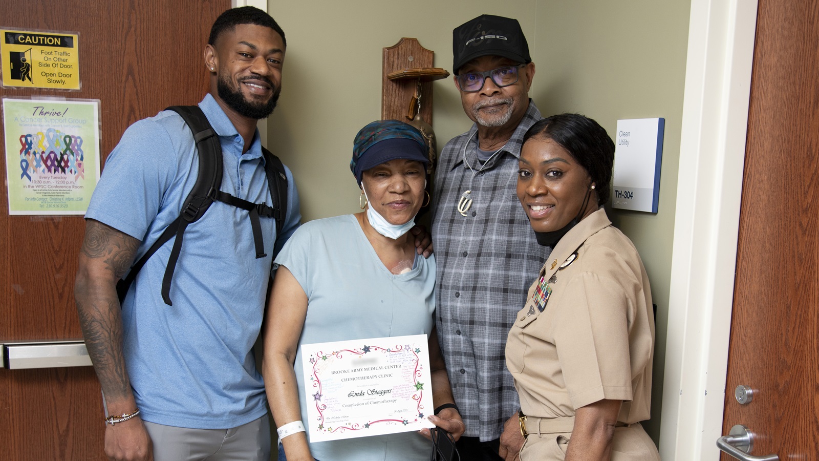 Linda Staggers poses with her husband, retired Master Chief Petty Officer Fred Staggers, son, Theo Staggers, and daughter, Master Chief Petty Officer Rosalyn Martin, after ringing the bell in the Hematology/Oncology Clinic at Brooke Army Medical Center, Joint Base San Antonio – Fort Sam Houston, Texas, April 4, 2025. Ringing the “cancer bell” is a tradition signifying a patient’s successful completion of cancer treatment. (DoD photo by Jason W. Edwards)