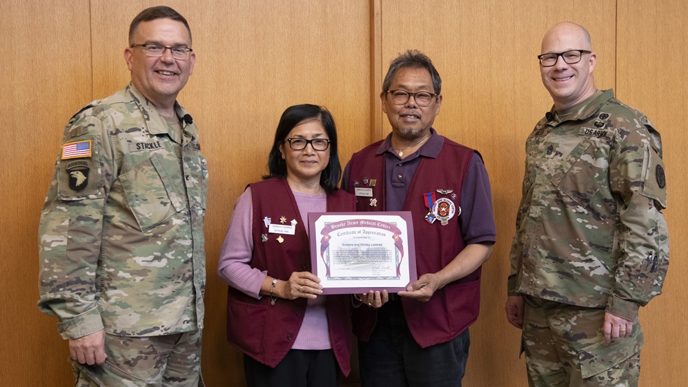Col. Mark Stackle, commander, and Command Sgt. Major Jan “Eddy” Miller present a certificate of appreciation to Ernesto and Shirly Lozares, who were recognized as Family of the Year, during the annual Volunteer Recognition Ceremony at Brooke Army Medical Center, Joint Base San Antonio – Fort Sam Houston, Texas, April 16, 2025. BAMC volunteers contributed more than 26,000 hours of service in 2024. (DoD photo by Jason W. Edwards)