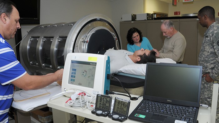 Dr. Victor Convertino, second from right, works with colleagues to place monitors on a volunteer in the U.S. Army Institute of Surgical Research lower body negative pressure chamber to collect physiological data as part of a research protocol.