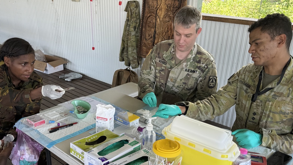 Service members make blood smears as part of the disease surveillance efforts at No Sick Soljia 2025 in Wewak, Papua New Guinea. From left to right: LT Lynelle Lassah (PNGDF), MAJ Brian Vesely (WRAIR-AFRIMS), LT Rhys Izuagbe (ADF).