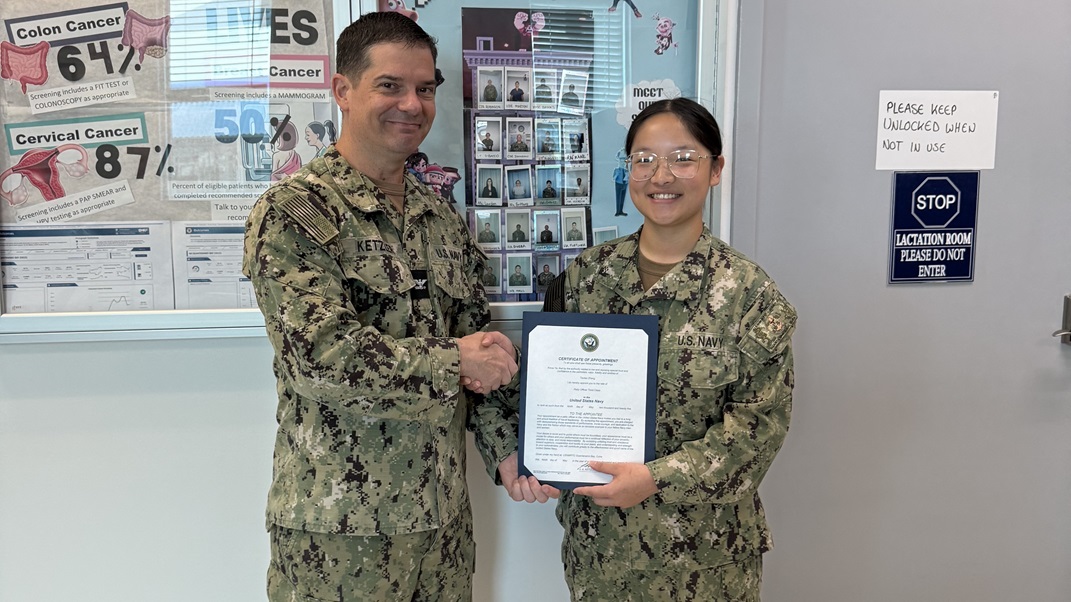 Capt. James Ketzler, executive officer of U.S. Navy Medicine Readiness and Training Command Guantanamo Bay, presents Hospital Corpsman 3rd Class Taotao Zhang with her certificate of appointment to Petty Officer 3rd Class, May 14, 2025. Zhang works in primary care and has served in the Navy for one year.