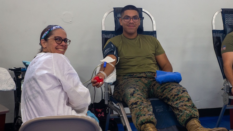 A Naval Hospital Guam civilian employee smiles while U.S. Marine Corps Pfc. Alexis Vasquez, small arms repair technician, Headquarters Company, Marine Corps Base Camp Blaz, donates blood during Camp Blaz’s first blood drive on MCB Camp Blaz, Guam, June 3, 2025. Camp Blaz partnered with Armed Services Blood Program Donor Center Guam and Naval Hospital Guam to help host a blood drive. (U.S. Marine Corps photo by Lance Cpl. Afton Smiley)