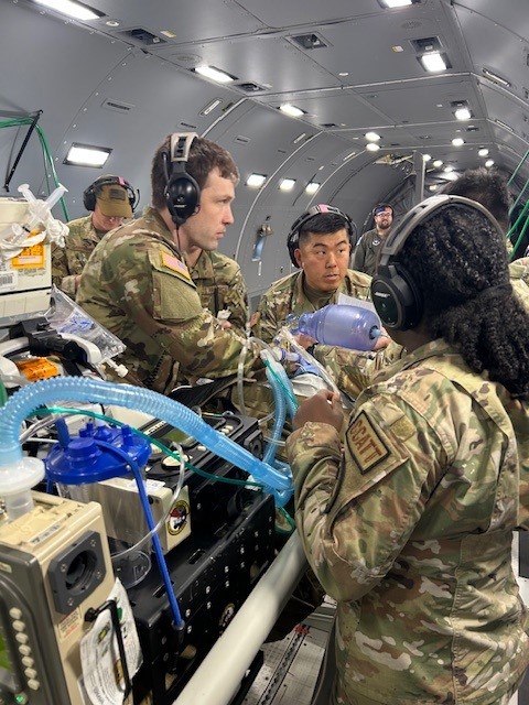 Members of the U.S. Army Institute of Surgical Research Burn Flight Team work with a U.S. Air Force Critical Care Air Transport team provide care to a simulated patient during a joint training exercise aboard a cargo aircraft.