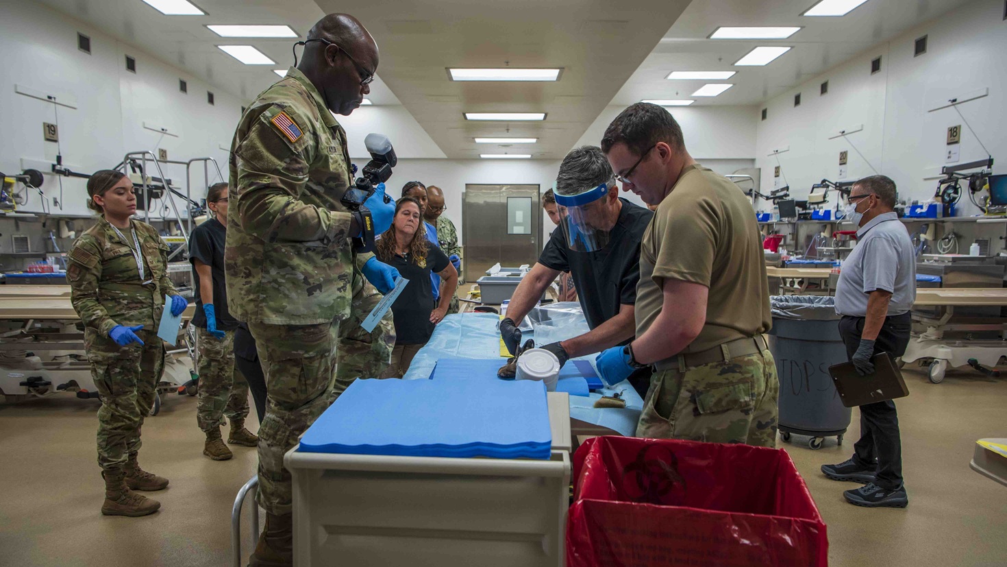 Dr. Edward Mazuchowski (third from right), Armed Forces Medical Examiner System forensic pathologist, cuts open a boot recovered from the 1952 Colony Glacier air crash site, at the AFMES, Dover Air Force Base, Delaware, Aug. 13, 2025.