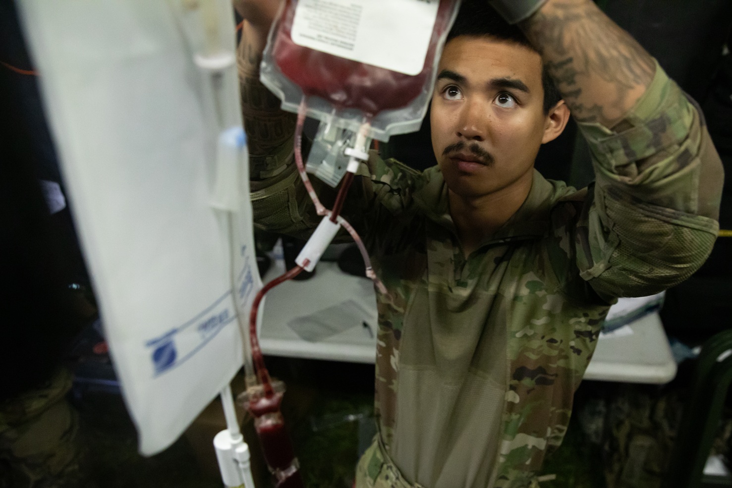 Technician hooking up a bag of blood to an IV pole