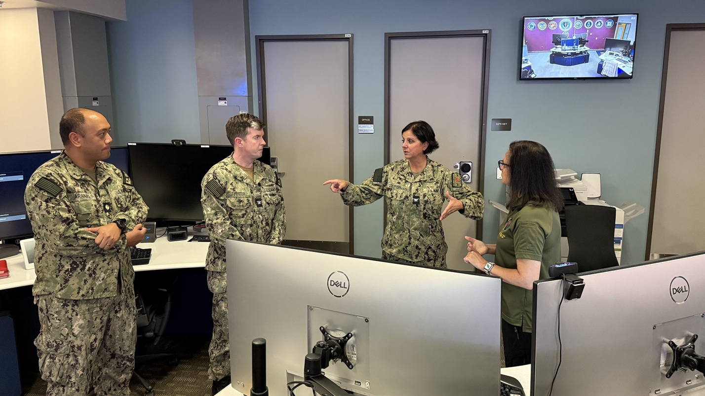During a visit Sept. 3 to the Virtual Medical Operations Center (VMOC) at Naval Medical Center San Diego (NMCSD), Defense Health Network Pacific Rim’s new Deputy Director Capt. Kathleen Cooperman (second from right) talks with Lt. Cmdr. Leonard Aranas (left), NMCSD’s director of medical services, Capt. David Foster (second from left), NMCSD’s director of branch clinics, and Lynn Campbell (right), nurse.