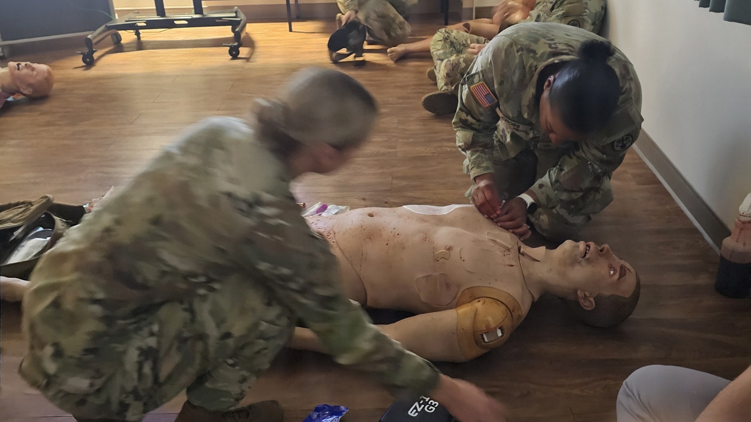 In the critical MASCAL exercise, 2nd Lt. Elizabeth Ostrowski, RN (left) confidently supported Pfc. Sharleeza Cross, LPN (right) as she performed needle decompression on a casualty. Meanwhile, 2nd Lt. Kayla Solberg (back) efficiently provided care to another injured individual. 