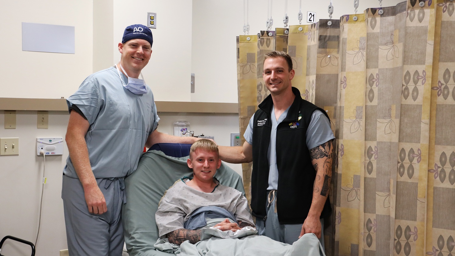 Army Spc. Grant Dickerson poses for a photo with Cmdr. Daniel Hammer, left, maxillofacial surgeon and director of the Maxillofacial Restoration Program at Naval Medical Center San Diego, and Lt. Cmdr. Stephen Moreno, oral maxillofacial surgery residency program assistant director, before he undergoes a jaw-in-a-day surgery. Dickerson had the surgery to remove a tumor that had destroyed two-thirds of his lower jaw and rebuild the damaged portion. (DoW photo by Regena Kowitz)