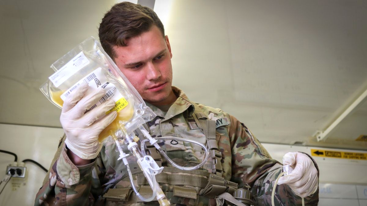 U.S. Army Pfc. Jaritt Louthan, a medical lab technician with 432nd Blood Support Detachment, 28th Combat Support Hospital, 44th Medical Brigade, and a native of Cleveland, re-hydrates prototype Freeze-Dried Plasma during an airdrop test Sept. 19, 2019 at Fort Bragg, N.C. In a major advancement for military medicine and battlefield survival, the Defense Health Agency helped secure Food and Drug Administration approval for this lifesaving product, designed to stop uncontrolled bleeding in the most remote environments. Marketed under the name EZPLAZ Freeze-Dried Plasma and manufactured by Teleflex, the product provides front-line military medical providers with a shelf-stable, highly portable treatment for severe injuries when traditional blood products are unavailable. FDP is managed by the DHA’s Warfighter Protection and Acute Care team under the Portfolio Acquisition Executive for Medical Products. (U.S. Army photo by Sgt. Brian Micheliche.Released)