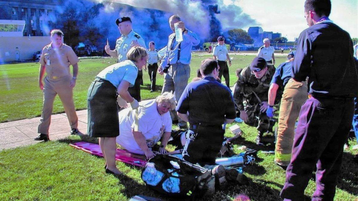 Medical professionals treat injuries outside the Pentagon in Washington, D.C., on the morning of Sept. 11, 2001. Retired Air Force Maj. Bridget Larew and retired Army Maj. Lorie A. Brown, medical personnel with the DiLorenzo Pentagon Health Clinic’s, orchestrated by triage and treatment to save the wounded while retired Army Col. (Dr.) James Geiling raced to the scene. Across the country, U.S. Public Health Service Lt. Cmdr. (Dr.) Susan Lippold volunteered to help at ground zero in New York. These brave military medical heroes reflect on the significance of preparing for a disaster response, and the chaos of that fateful day 25 years later. (U.S. Navy photo by: Journalist 1st Class Mark D. Faram)