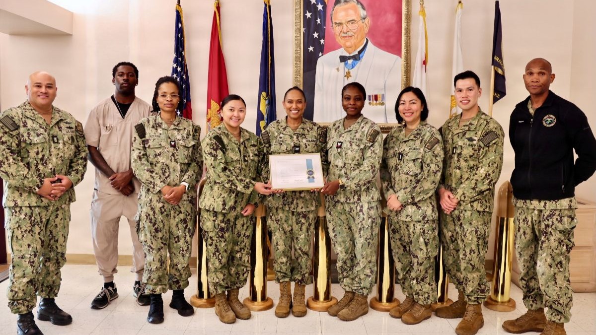 Capt. Janiese Cleckley (center), director, Naval Hospital Twentynine Palms, Master Chief Richard Moreno (left), senior enlisted leader, and Lt. Cmdr. Nathan Magare (right), director for clinical support services, present the College of American Pathologists reaccreditation certificate to the laboratory team at Naval Hospital Twentynine Palms, Calif., Sept. 17, 2026. (U.S. Navy photo by Christopher Jones, NMRTC/NH Twentynine Palms public affairs officer).