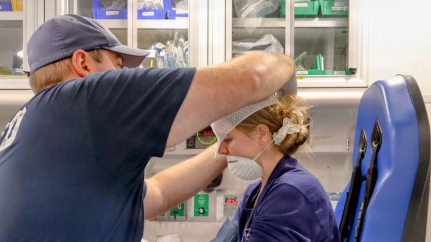 Photo By Maria Scott | A first responder with Naval District Washington (NDW) Fire and Emergency Services applies cranial bandaging to Hospital Corpsman 2nd Class Elisabeth Basham aboard an ambulance during a full-scale Mass Casualty Incident (MCI) active assailant drill at Spring Ridge Middle School. Basham, assigned to Navy Medicine Readiness and Training Command (NMRTC) Patuxent River, portrayed a simulated casualty with a shrapnel injury to the right head and eye caused by glass and flying debris. The joint exercise brought together regional first responders, state police, and military personnel to evaluate mass casualty triage protocols, advanced emergency care, and interagency coordination.