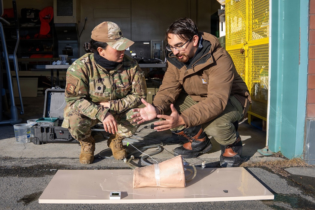 Two military personnel outside, kneeling down and looking at a package