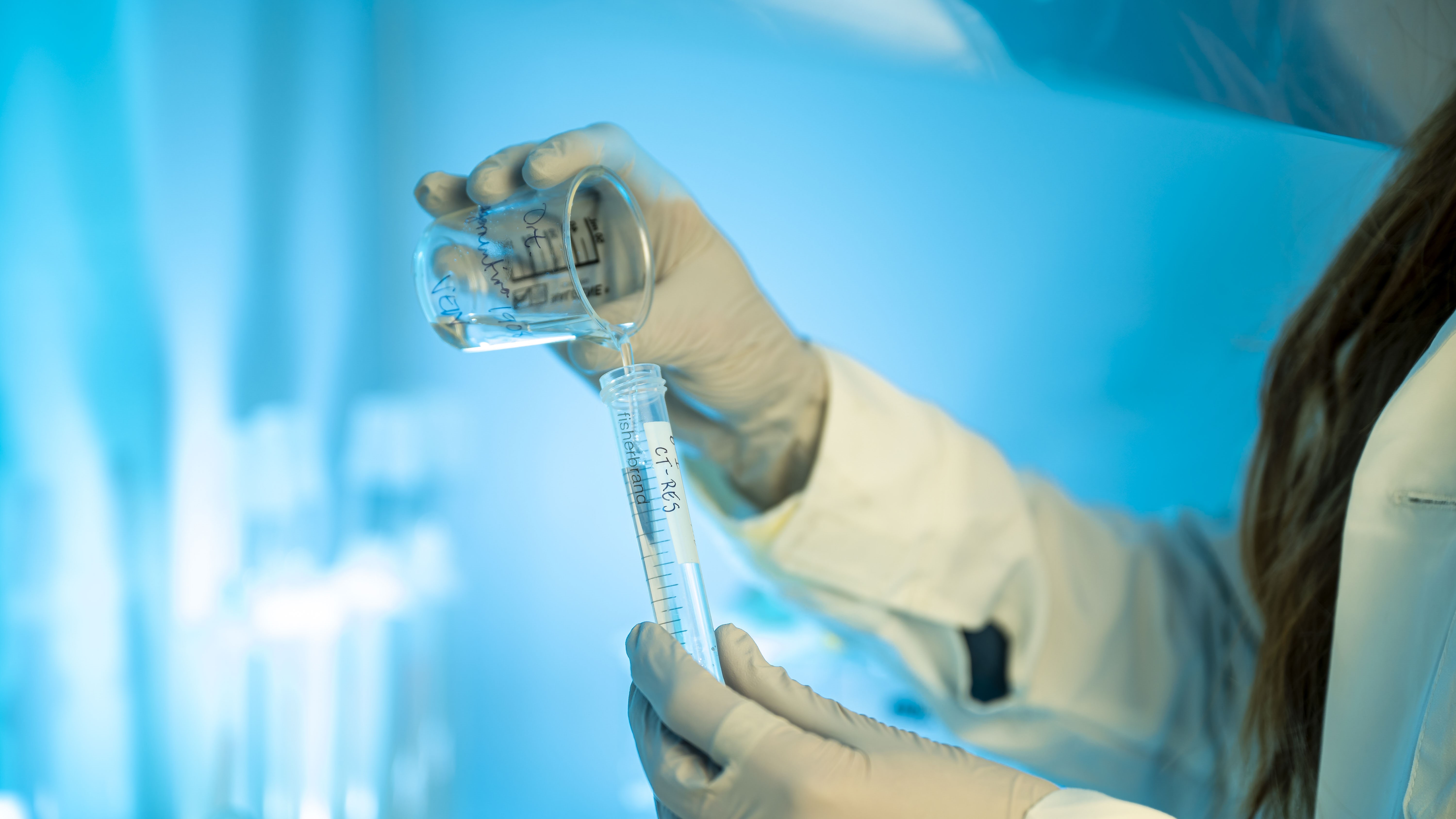 scientist transfers fluid between beakers