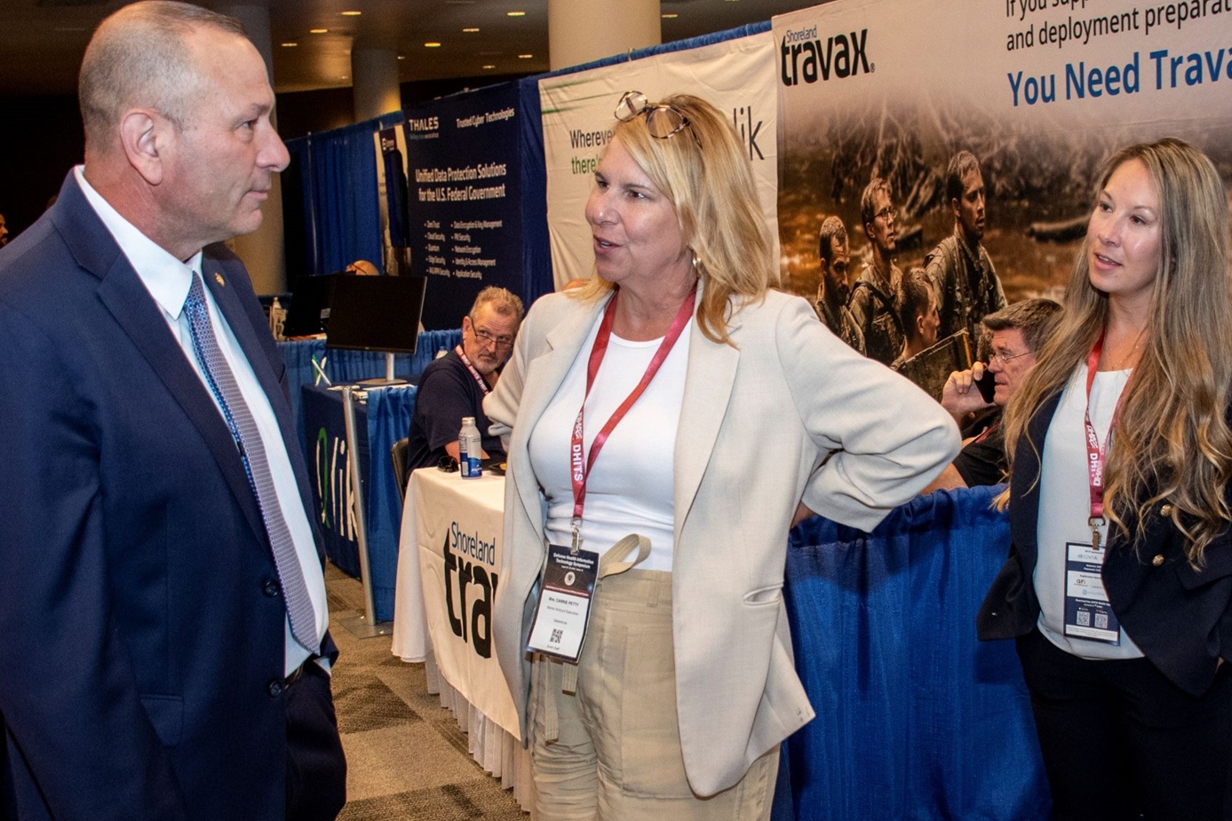 Pat Flanders, chief information officer for the Defense Health Agency, visits with government officials and vendors while visiting the exhibition hall during the 2024 Defense Health Information Technology Symposium in Dallas, Texas, Aug. 21.