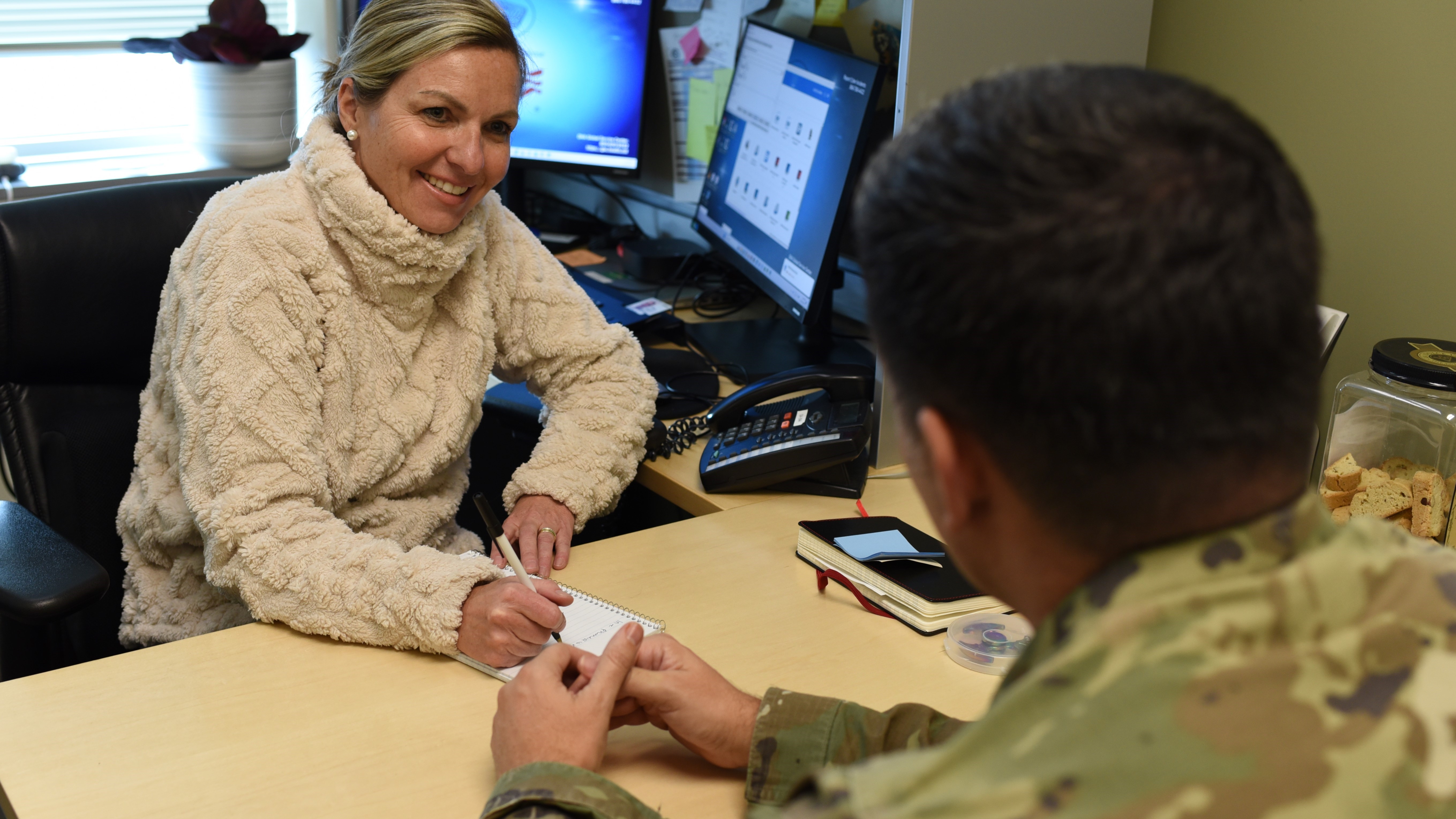 Woman and soldier talk across a desk